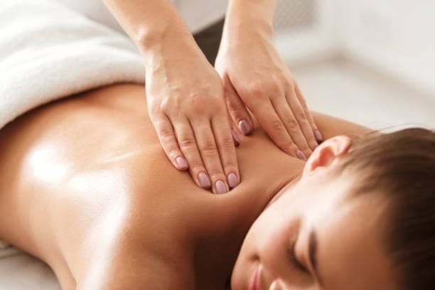 Massage therapist performing soft tissue massage on a client's upper back and shoulders